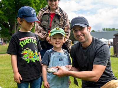 Father, sons, and instructor holding a rainbow trout and smiling