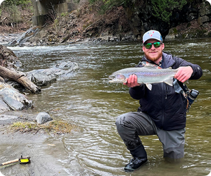 Angler with steelhead rainbow trout in river