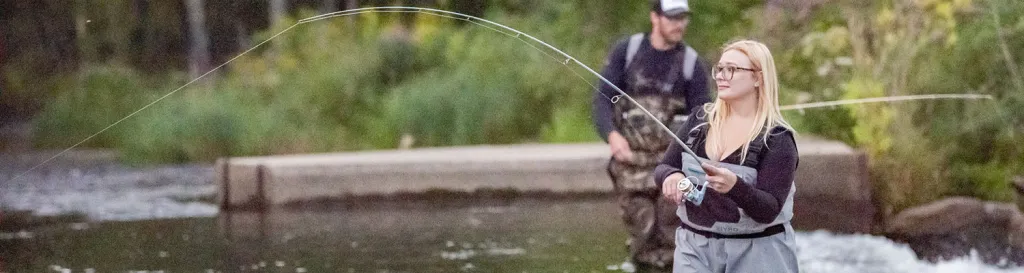 women and man in waders fly fishing in river